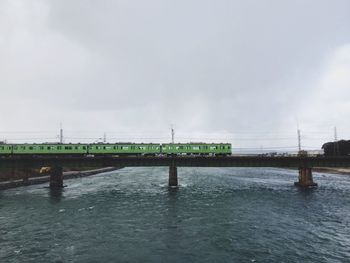 Bridge over river against cloudy sky