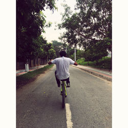 Rear view of man riding motorcycle on road