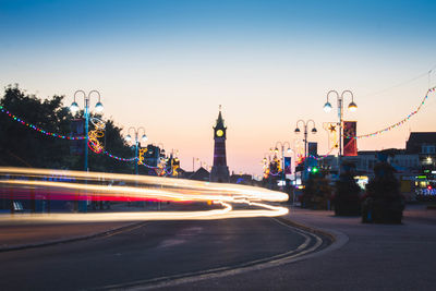 Light trails on road in city against sky