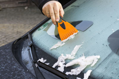 Hand scraping ice off windshield