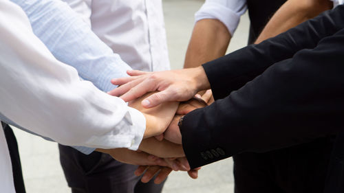 Midsection of men and women holding hands