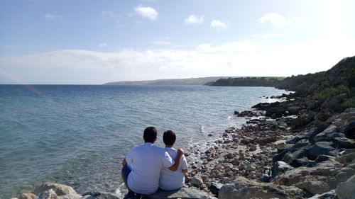 Rear view of people on beach against sky
