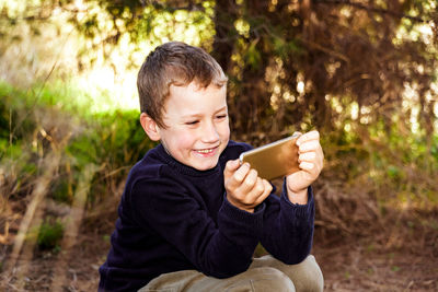 Portrait of boy holding smart phone outdoors