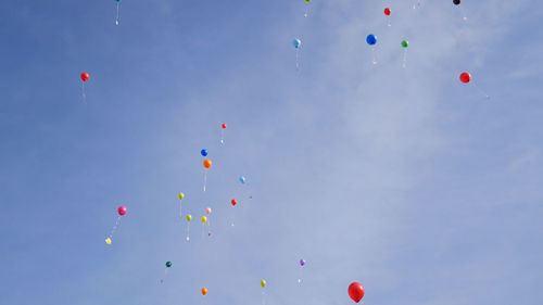 Low angle view of balloons flying against sky