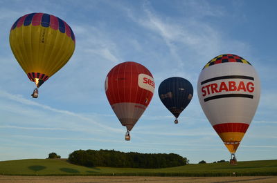 Hot air balloon flying over field against sky