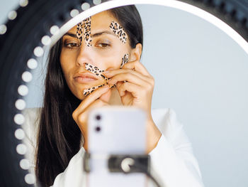 Young beautiful brunette woman beauty blogger with long hair showing face taping with leopard tapes