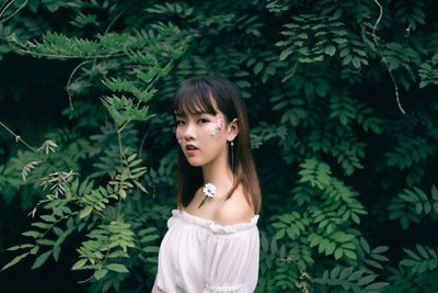 Portrait of woman standing against plants