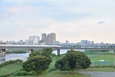 Bridge over river by buildings against sky in city