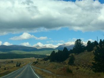 Empty road along landscape and mountains against sky