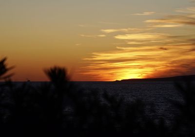 Scenic view of silhouette field against orange sky