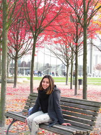 Portrait of smiling young woman sitting on park during autumn