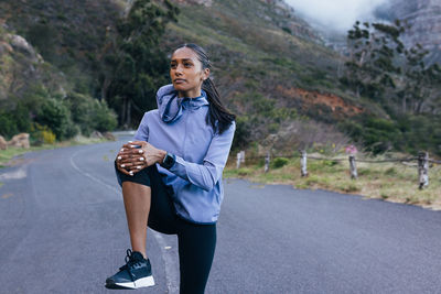 Portrait of young woman exercising on road