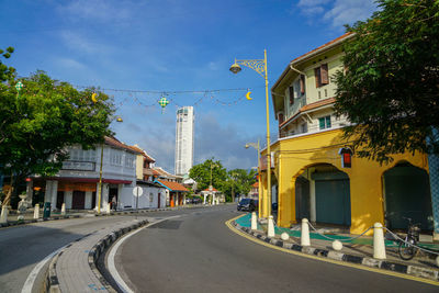 Road by buildings in city against sky