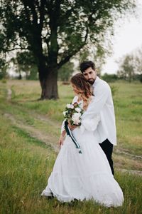 Bride and bridegroom standing on field