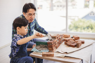 Father teaching son to make brick wall at workshop