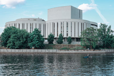 View of building by lake against cloudy sky