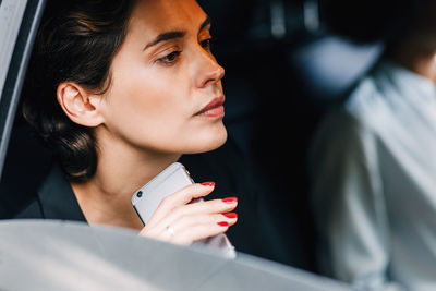 Close-up of woman holding mobile phone while sitting in car