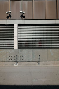 Security cameras on wall by road in city during sunny day