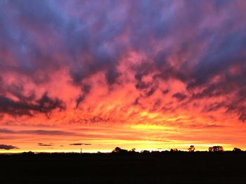 Scenic view of dramatic sky over silhouette landscape during sunset