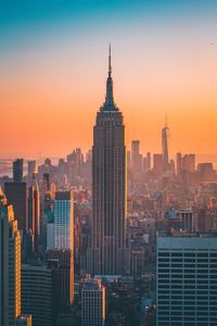 Empire state building in cityscape at sunset