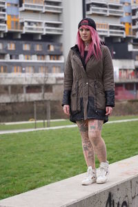 Young woman walking on retaining wall at lawn in city