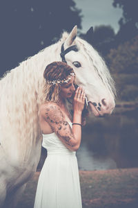 Portrait of young woman with horse standing outdoors