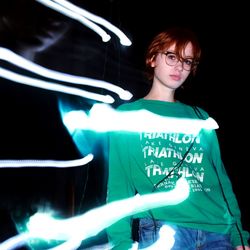 Young woman standing by illuminated text against black background