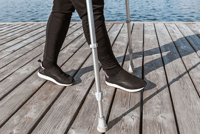 Low section of man standing on pier at sea