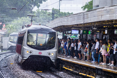 People standing at railroad station platform during rainy season