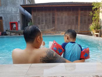 Rear view of father and son in swimming pool