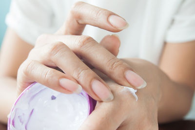 Close-up of woman sunscreen applying on hand at home