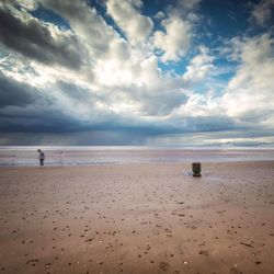 Scenic view of beach against cloudy sky