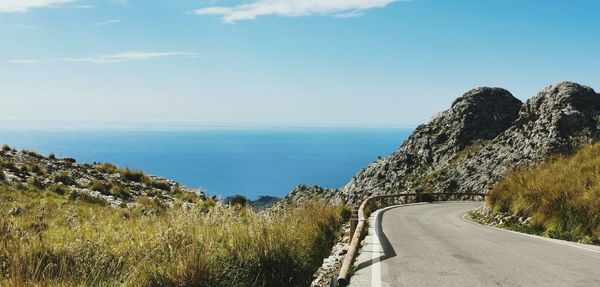 Scenic view of road by sea against sky