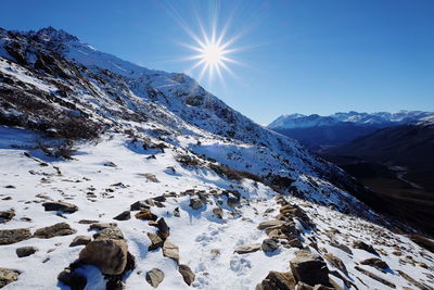 Scenic view of snowcapped mountains against sky on sunny day