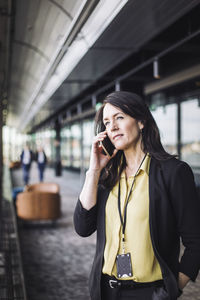 Female entrepreneur talking on mobile phone while standing at workplace
