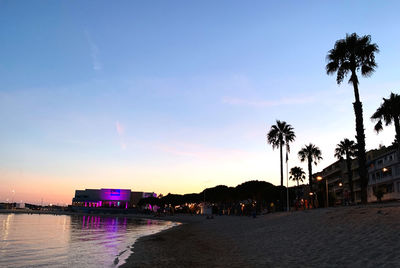 Silhouette palm trees on beach against sky during sunset