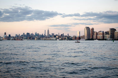 Sea by buildings against sky during sunset