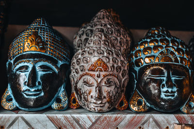 Handmade gold plated buddha face masks on a counter in a street shop on the island of bali