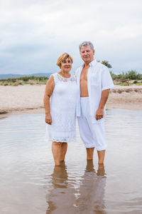 Portrait of senior couple standing in water at beach