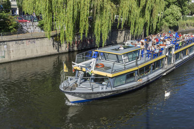 Boats sailing on river by trees