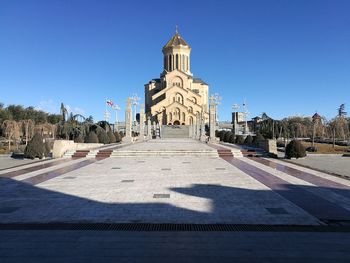 Street amidst buildings against clear blue sky