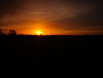 Scenic view of silhouette field against orange sky