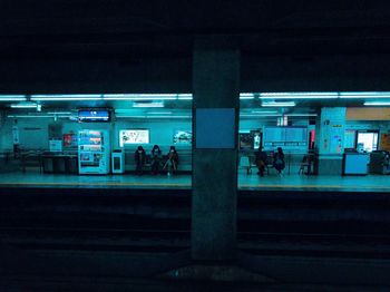 People waiting at railroad station platform at night