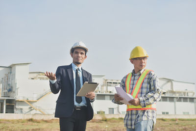 Man working with umbrella standing against sky