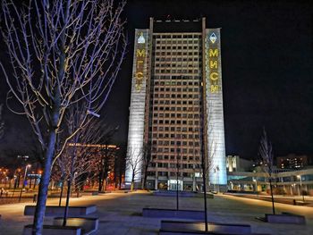 Illuminated building by street against sky at night