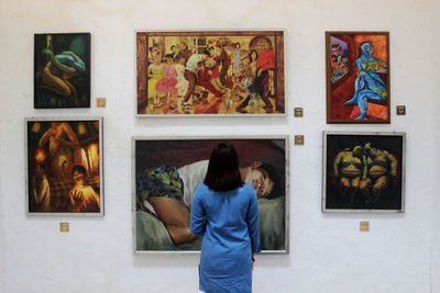 Rear view of woman standing in front of paintings