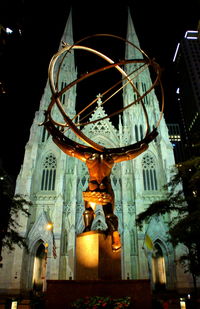 Low angle view of statue against illuminated temple at night