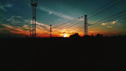 Low angle view of silhouette electricity pylon against sky