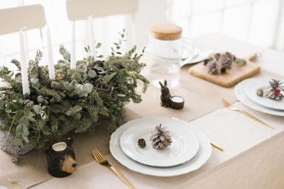 Stylish christmas table setting a composition of fir branches, white plates decorated with cones