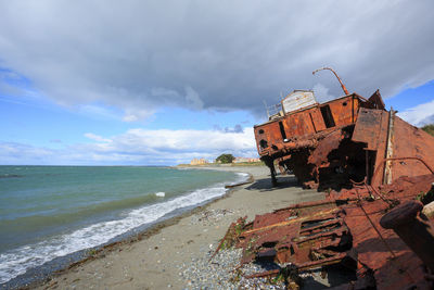 Abandoned ship on beach against sky